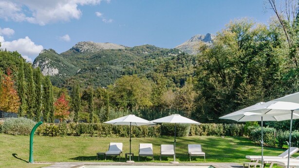 A swimming pool with lounge chairs and umbrellas, surrounded by greenery and mountains in the background. - Apartment in Camaiore with 2 bedrooms sleeps 4 (Camaiore)