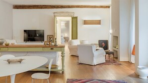 A living room with a wooden ceiling, a white sofa, a white armchair, a TV, and a fireplace. - Apartment in Camaiore with 2 bedrooms sleeps 4 (Camaiore)