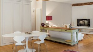 A dining area with a white table and chairs, a wooden floor, and a rustic ceiling beam. - Apartment in Camaiore with 2 bedrooms sleeps 4 (Camaiore)
