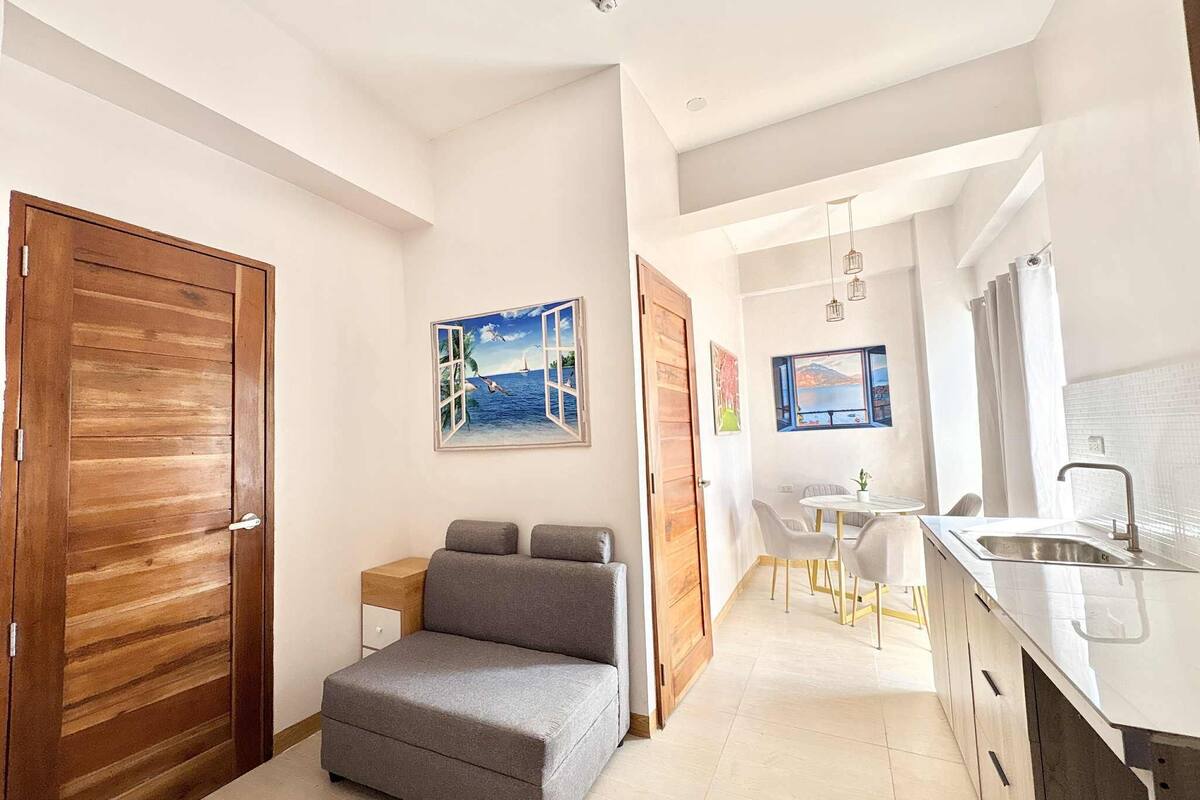 A modern kitchen with a sink and a dining area with a table and chairs.