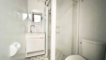 Un baño moderno con inodoro, lavamanos y ducha.