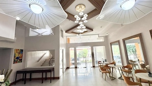 A spacious hotel lobby with a staircase, dining area, and large windows. - Palette Cebu The Almonds Boutique Aparthotel Near University of Cebu (Cebu City)