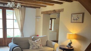 Un salon chaleureux avec un plafond en bois, un canapé, une table basse et une lampe.