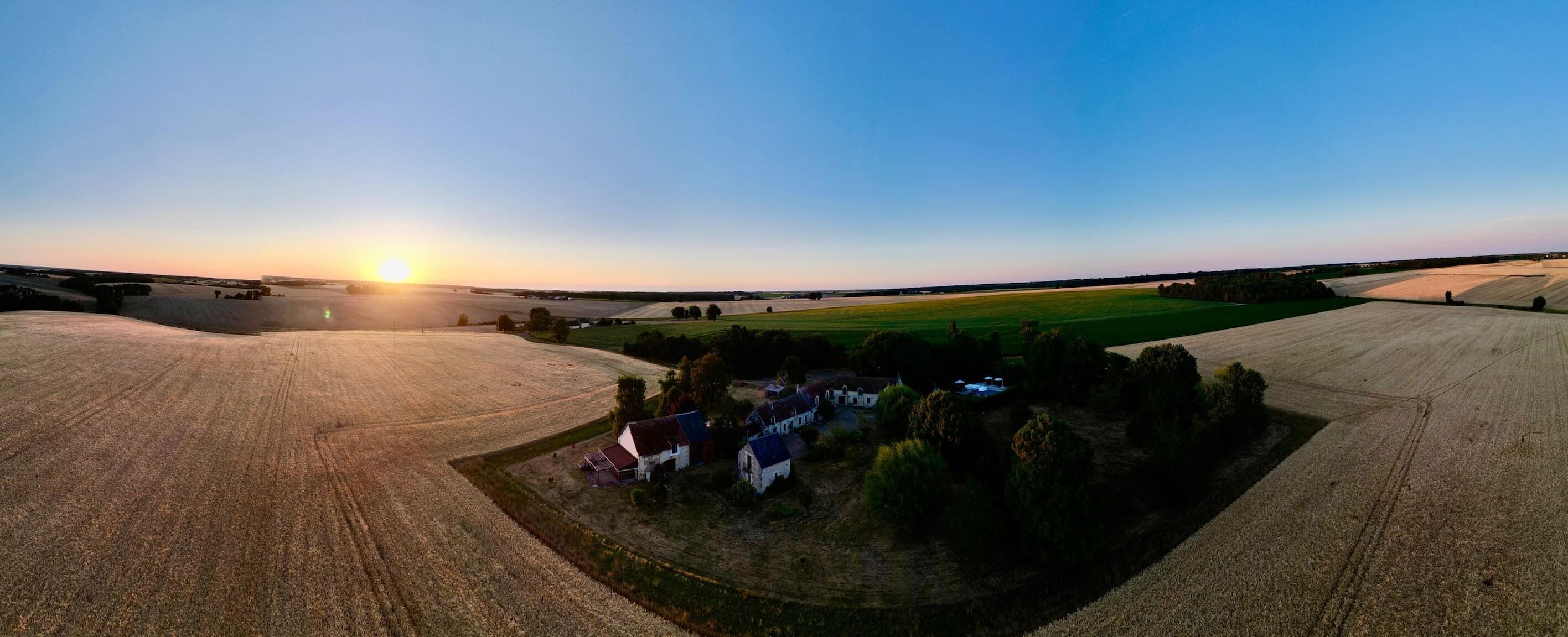 An aerial view of a rural landscape with fields and a small cluster of houses.