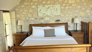 Ein hölzernes Bett in einem Zimmer mit Steinwänden und einer schrägen Decke.