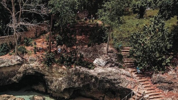 A natural pool with clear turquoise water, surrounded by rocky terrain and a staircase leading up. - Agapimou apartments H (Gaspar Hernandez)