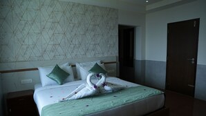 A hotel room with a bed, pillows, a nightstand, a wooden door, and a patterned wall. - Shola Heaven (Devikolam)