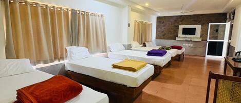 Une chambre d’hôtel avec trois lits, une télévision et un ventilateur de plafond.