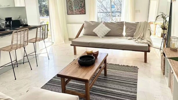 Ein modernes Wohnzimmer mit einer Couch, einem Couchtisch und einem Essbereich mit Stühlen.
