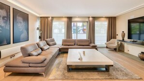 A modern living room with a sectional sofa, a coffee table, and a flat-screen TV. - Prestigious 5BR Avenue Foch Home - Arc de Triomphe (Paris)