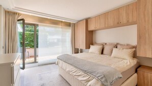 A bedroom with a large bed, a sliding glass door to a balcony, and wooden paneling on the walls. - Prestigious 5BR Avenue Foch Home - Arc de Triomphe (Paris)