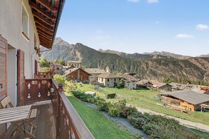 Un pueblo de montaña con casas de madera tradicionales, cielo despejado y vistas a las montañas circundantes.
