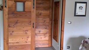 A room with a wooden door, a framed picture on the wall, and a tiled floor. - Apartment 'Maison Erica - Ozein' with Mountain View and Private Outdoor Area (Ozein)