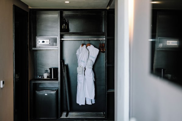 Habitación de hotel con minibar, microondas y perchero con batas.