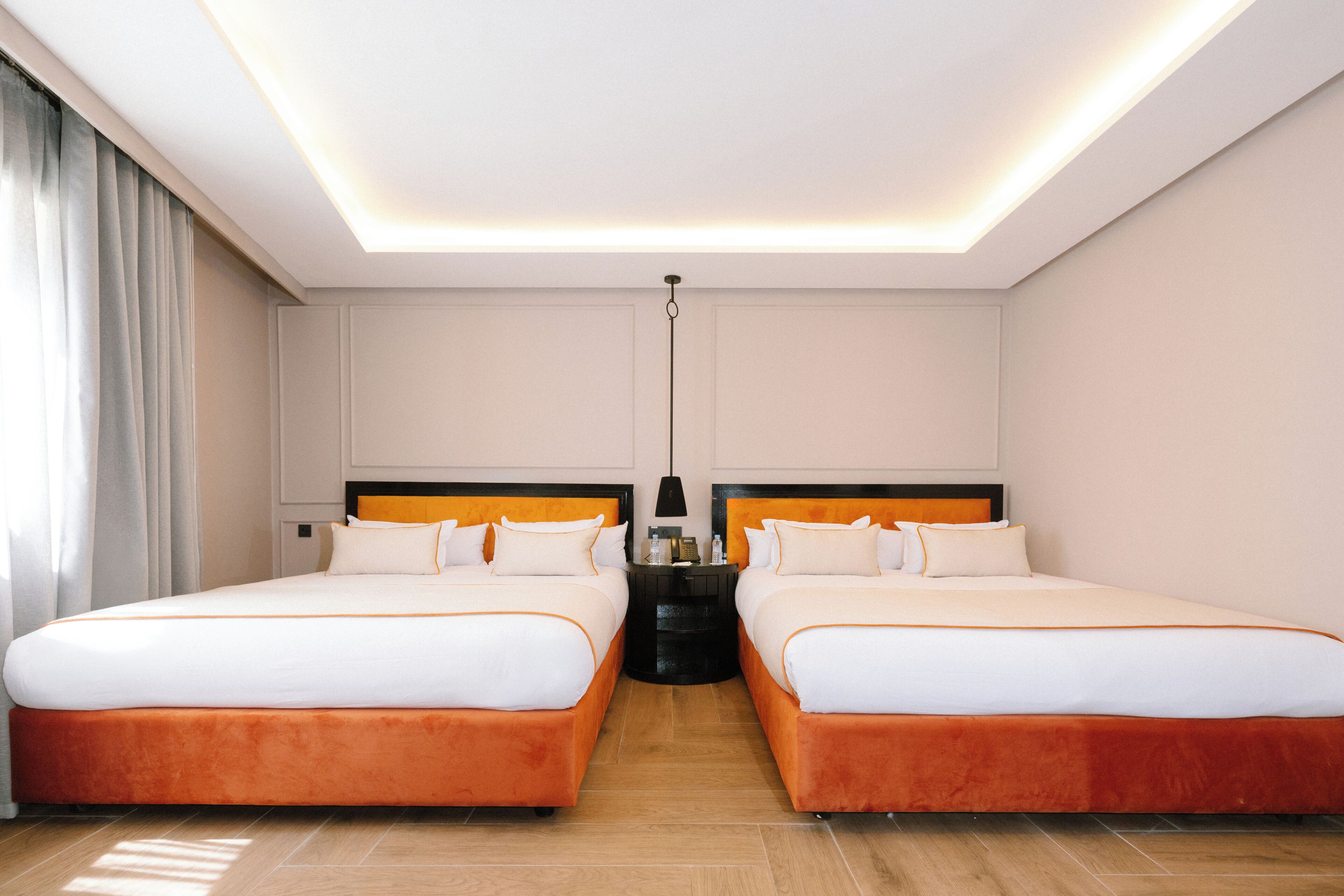 Habitación de hotel con dos camas, una mesita de noche, una lámpara y una luz en el techo.