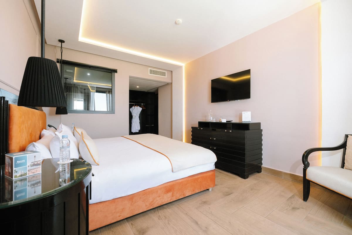 Una habitación de hotel con cama, televisión, cómoda y silla.