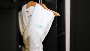 Una bata blanca con la leyenda 'Accidental Hotels & Resorts' colgada de una percha de madera.