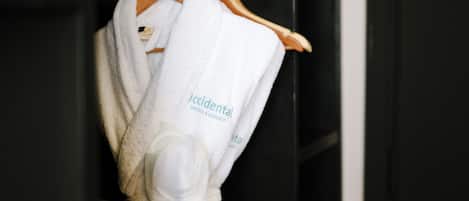 A white robe with 'Accidental Hotels & Resorts' text hanging on a wooden hanger.