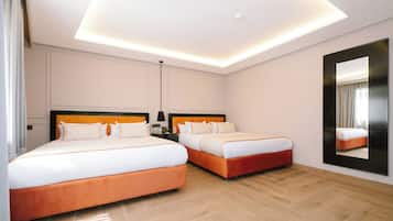 Une chambre d’hôtel avec deux lits, un grand miroir et un luminaire moderne au plafond.
