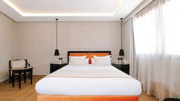 Habitación de hotel con una cama grande, dos mesitas de noche, una silla y una lámpara en el techo.