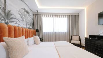 Una habitación de hotel con una cama grande, una silla, un aparador y un televisor en la pared.