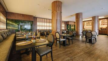 Um restaurante com chão de madeira, altos pilares de madeira e diversos tipos de assentos, incluindo mesas e cadeiras.