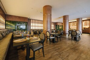 A restaurant with wooden flooring, high wooden pillars, and a variety of seating arrangements including tables and chairs. - Occidental Casablanca Medina (Casablanca)