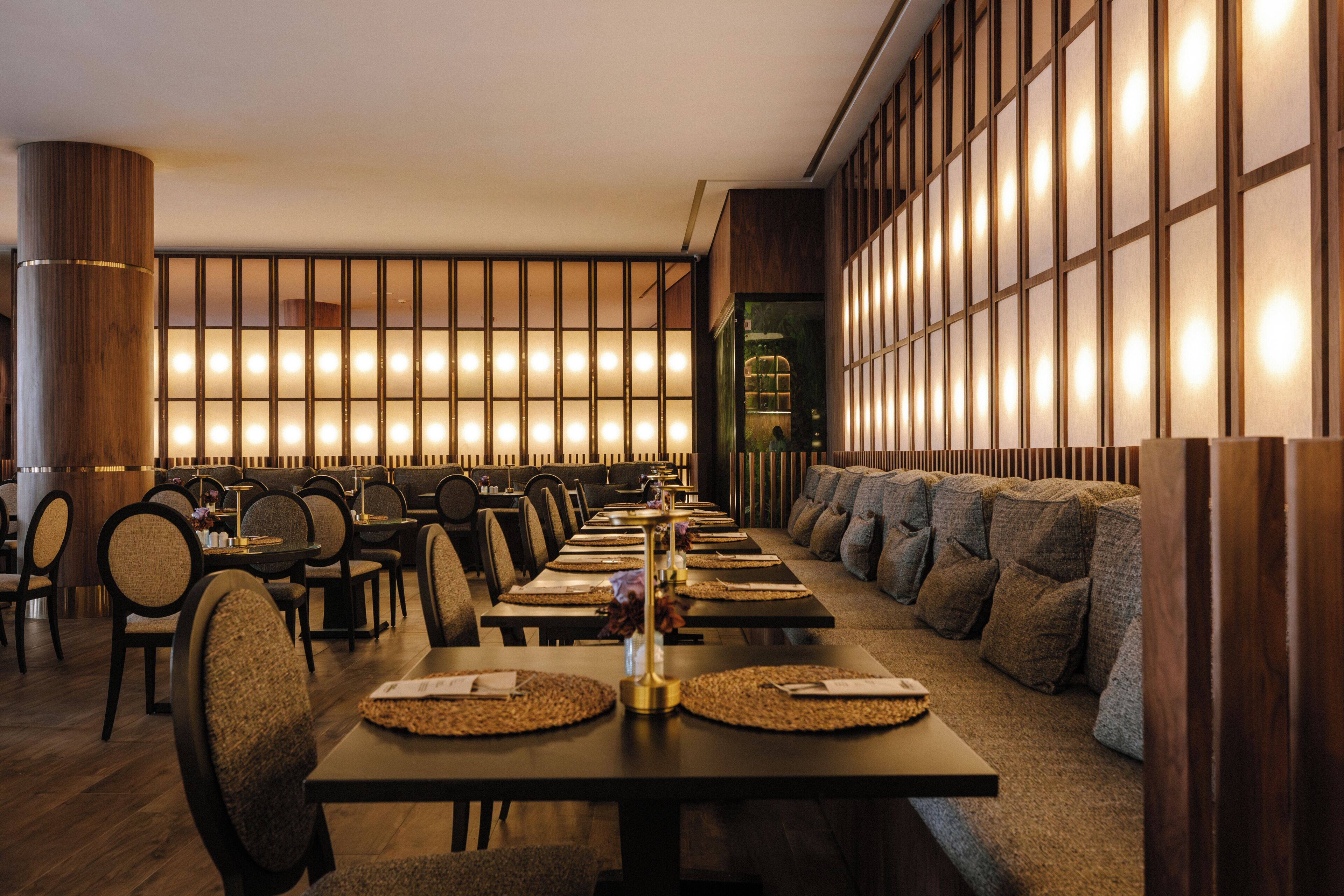 Un restaurant avec de longues tables, des chaises et un espace détente avec des coussins.