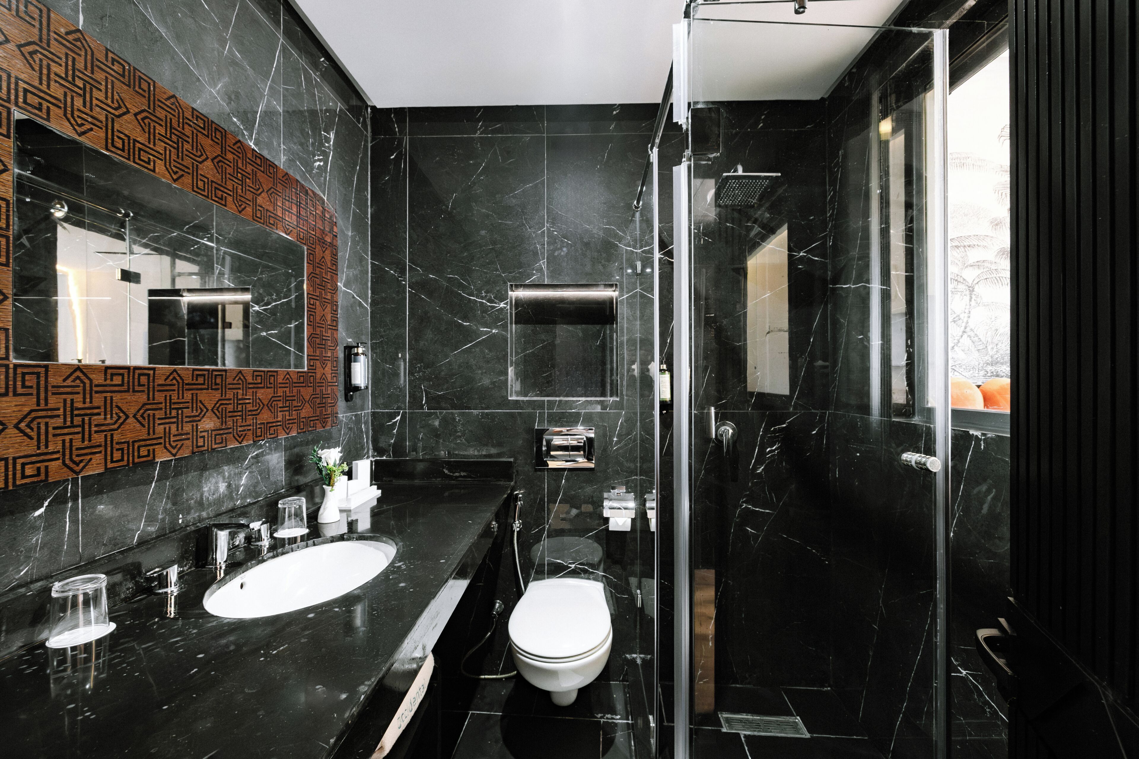 Un baño moderno con un espejo grande, dos lavamanos, un inodoro y una ducha con mampara de vidrio.