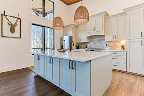 A modern kitchen with a large island, white cabinetry, and pendant lighting. - Riverstone Retreat | Ellijay, GA (Ellijay)