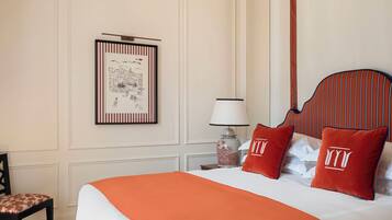 Habitación de hotel con una cama grande, una obra de arte enmarcada en la pared, una mesita de noche con lámpara y una silla.