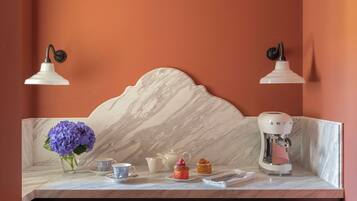 A kitchen counter with a marble backsplash, a coffee machine, and a vase of purple flowers.