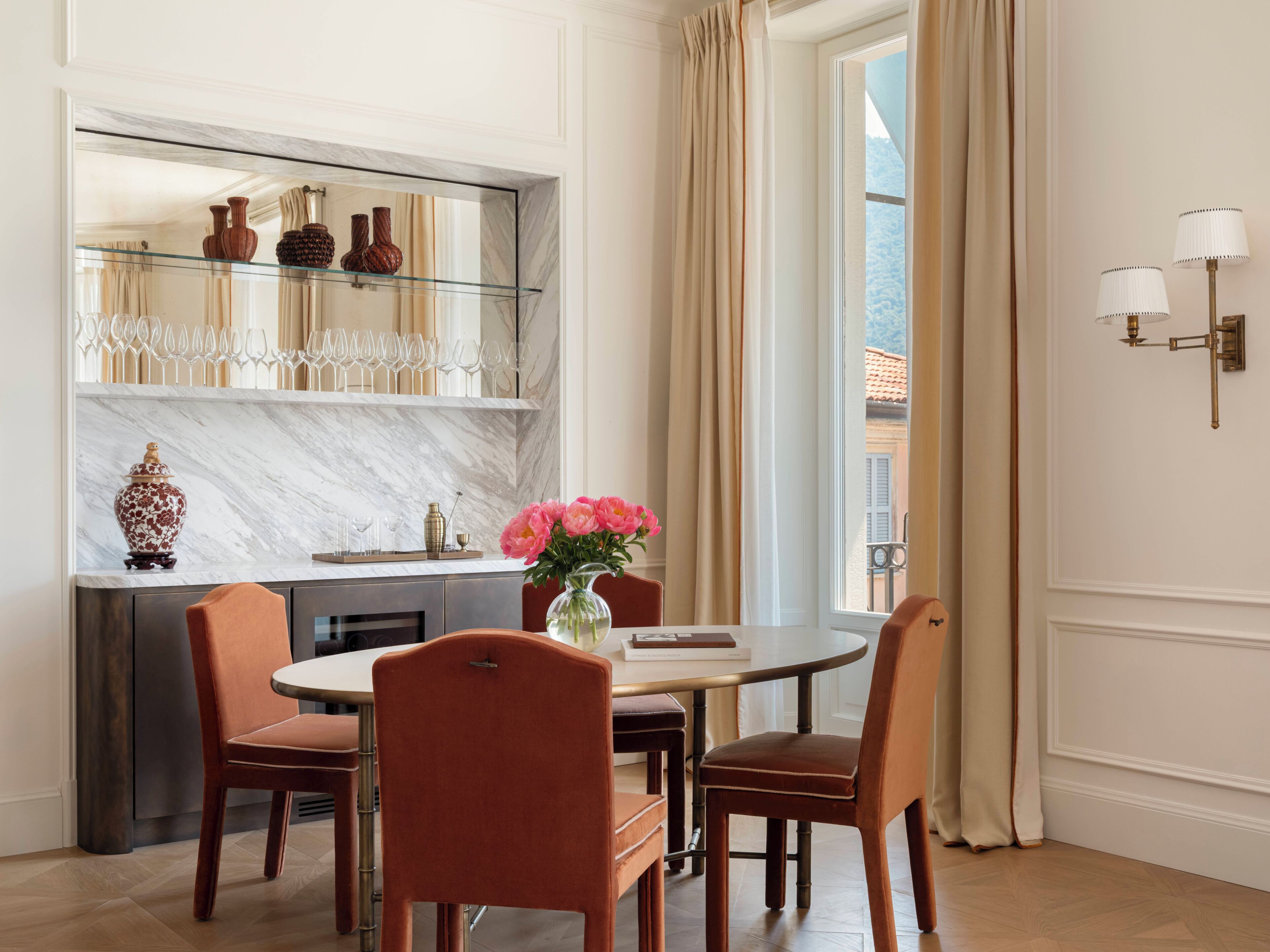 A dining area with a marble countertop, a vase with flowers, and a view of a snowy landscape through a window.