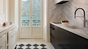 A kitchen with a view of a lake and mountains, a black and white checkered floor, and a modern faucet. - Miralago Luxury Apartments (Cernobbio)