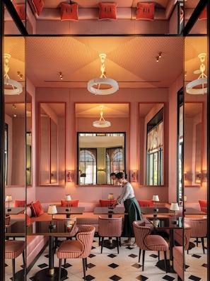 A restaurant interior with striped walls, red cushioned seating, and a central mirror. - Miralago Luxury Apartments (Cernobbio)