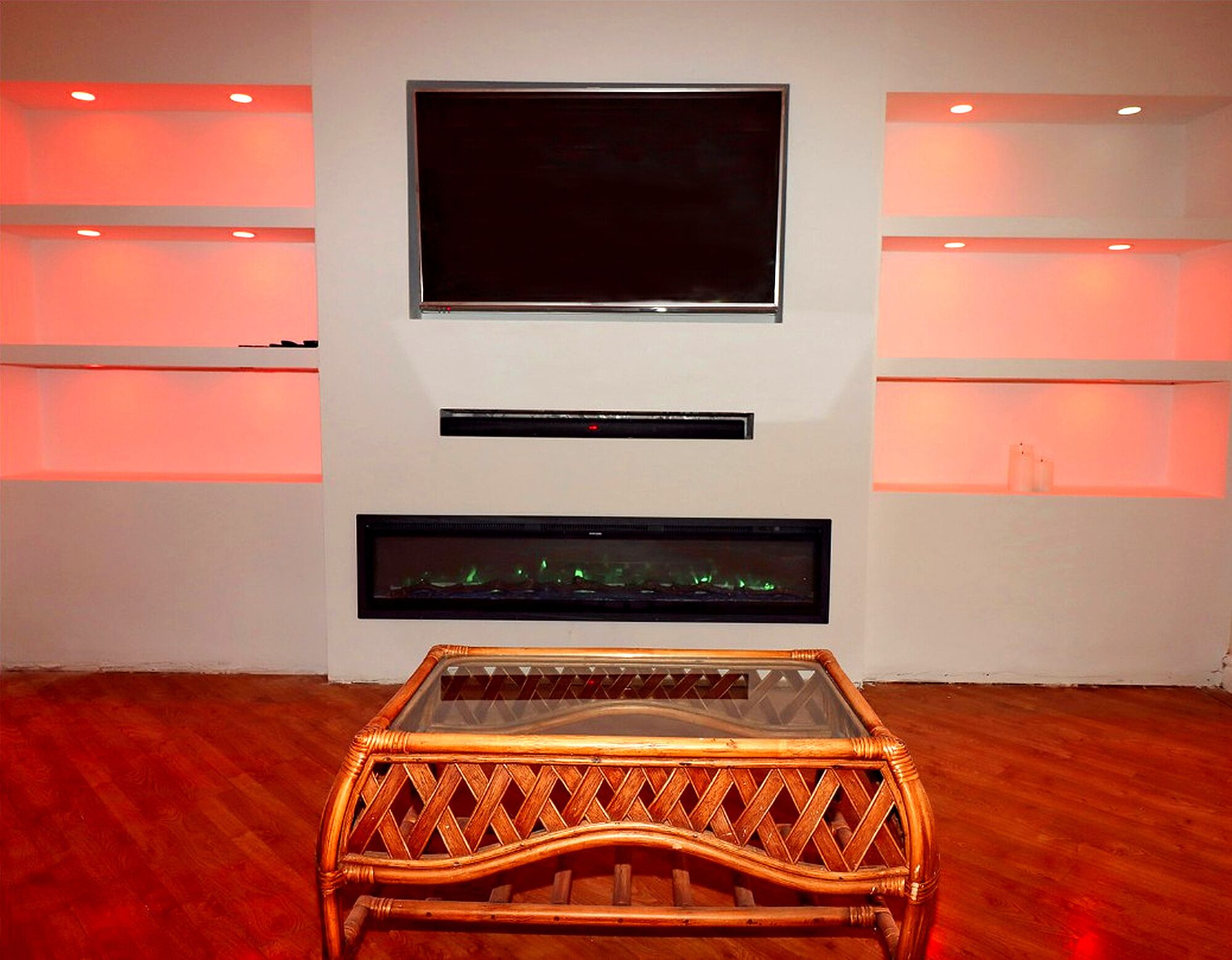 Ein Zimmer mit an der Wand montiertem Fernseher, einem Flachbildschirm und einem großen Bilderrahmen darunter.