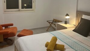A bedroom with a bed, a desk, a chair, and a window with a hanging light fixture. - Les Appartements De Lina - L'Architek (La Grande-Motte)