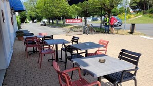 An outdoor seating area with tables and chairs, a sign indicating a restaurant, and a bicycle parked nearby. - Le Saint Benoist (Aizenay)
