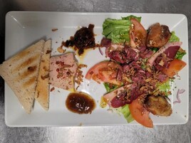Un plato con ensalada, rebanadas de carne y dos tostadas.