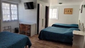 A room with two beds, a desk, a chair, and a television on the wall. - Le Saint Benoist (Aizenay)