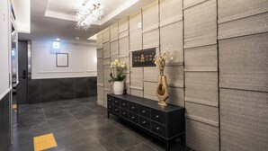 A modern hotel lobby with a black console table, a potted plant, and a decorative vase. - Incheon Hound New Town Branch (Incheon)