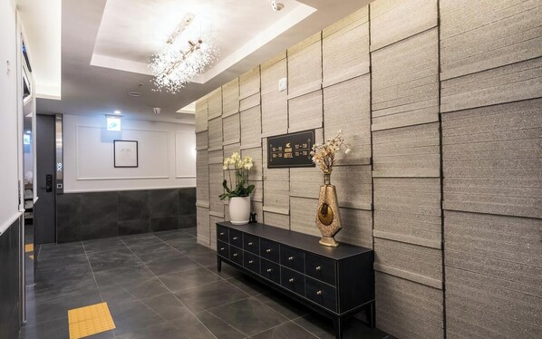 A modern hotel lobby with a black console table, a potted plant, and a decorative vase. - Incheon Hound New Town Branch (Incheon)