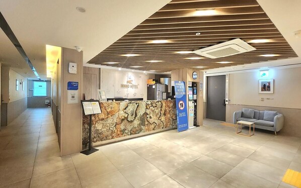 A hotel reception area with a stone wall, a reception desk, a sofa, and a vending machine.