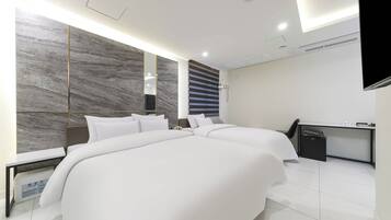 Una habitación de hotel moderna con dos camas, un escritorio y un espejo grande.