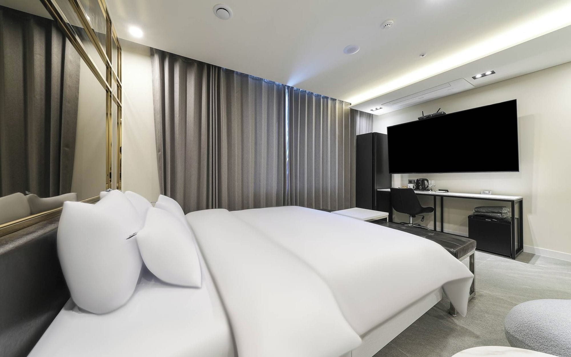 Een moderne hotelkamer met een groot bed, een bureau, een flatscreen televisie en een spiegel.