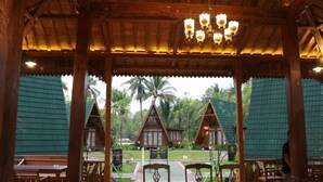 Ein hölzernes Pavillon mit Fliesenboden und Tischen und Stühlen, die zum Essen bereitstehen.