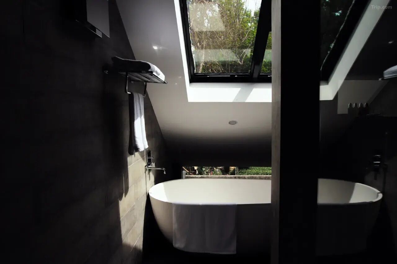 Ein modernes Badezimmer mit Oberlicht, einer freistehenden Badewanne und einem separaten Waschbereich.