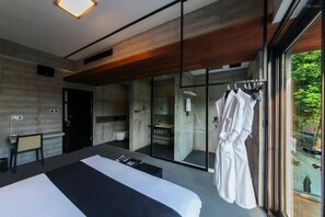 A modern hotel room with a large bed, a seating area, a bathroom, and a view of the outdoors. - Hangzhou Chunyin Chunshan Hotel (Hangzhou)