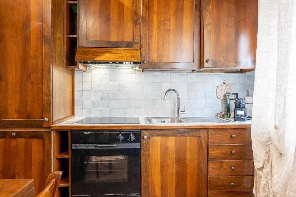 A kitchen with wooden cabinets, a built-in oven, and a sink.