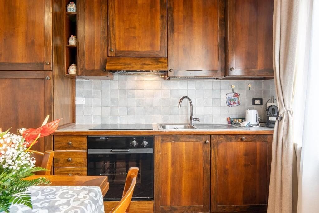 A kitchen with wooden cabinets, a dishwasher, a sink, and a table with a patterned tablecloth.
